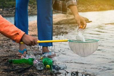 Low section of volunteers removing plastic bottles from lake