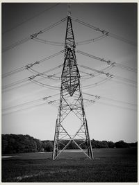 Low angle view of electricity pylon on field against sky