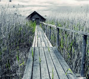 Wooden footbridge by sea against sky
