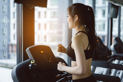 Woman listening music while exercising on treadmill in gym