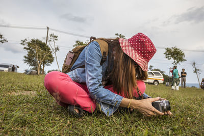 Women relaxing on field against sky