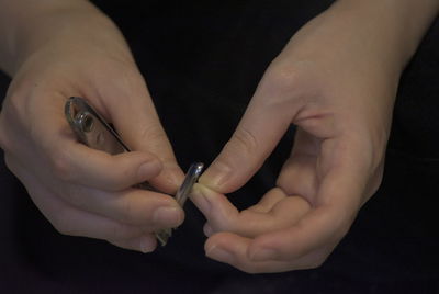 Close-up of woman holding hands over black background