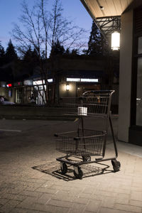 Sidewalk by illuminated street in city at night