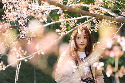 Portrait of young woman standing against plants
