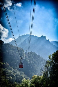 Overhead cable cars over mountains against sky