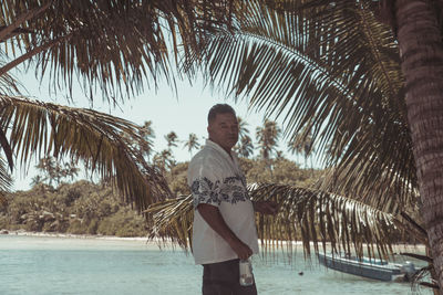 Man standing by palm tree against sky