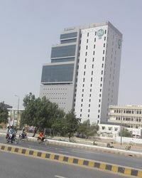 Cars on road by buildings against clear sky