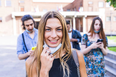 Portrait of smiling young woman walking with friends outdoors