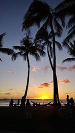 Silhouette palm trees on beach against sky during sunset