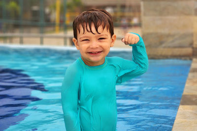 A smiling happy boy in the blue swimming pool having fun and playing on a sunny day