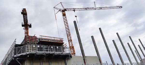 Low angle view of crane at construction site against sky