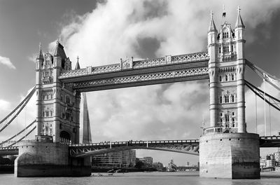 Low angle view of tower bridge over thames river against cloudy sky