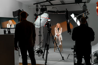 Art event with woman model posing barechested on stool in studio building