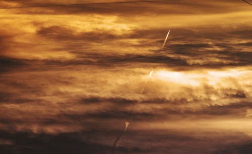 Low angle view of vapor trails in sky during sunset