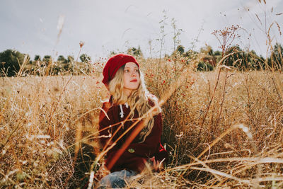 Beautiful woman looking away while sitting amidst plants