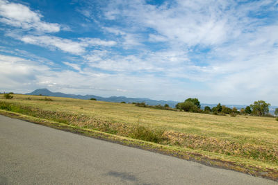 Scenic view of road amidst field against sky