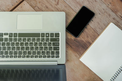 High angle view of laptop and smart phone with book on table