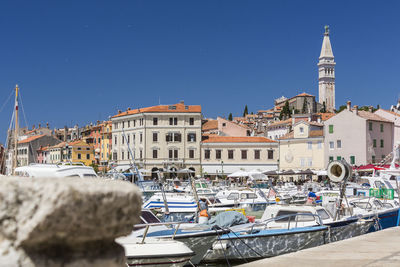 Boats moored at rovinj harbor against clear blue sky