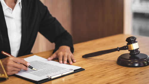 Midsection of man reading book on table