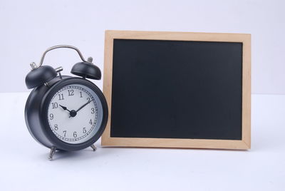 Close-up of clock on table against white background