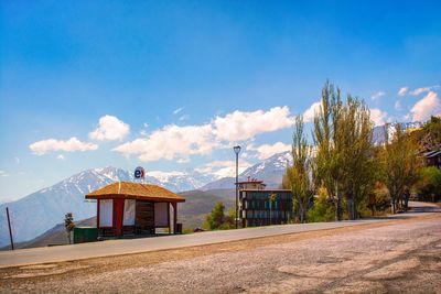 Houses by trees against blue sky