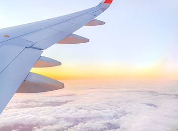 Airplane flying over sea against sky during sunset