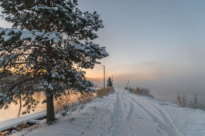 Snow covered field against sky during winter