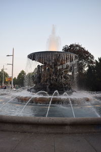Fountain in city against clear sky