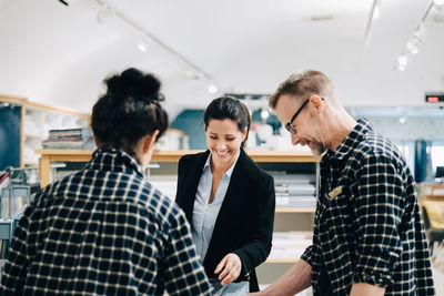 Male and female workers assisting female customer in store