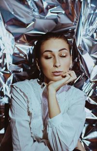 Close-up of woman with eyes closed against silver paper