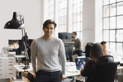 Portrait of male entrepreneur leaning on desk in office