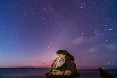 Scenic view of rock formation in sea against sky at night