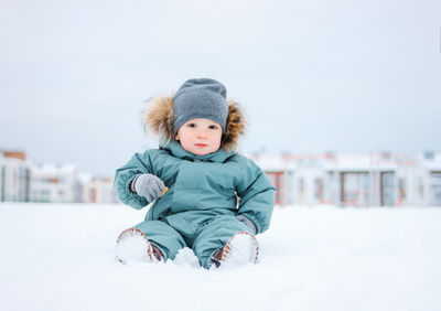 Cute boy in snow against sky during winter