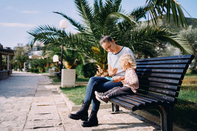 Portrait of woman sitting on bench at park