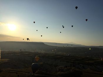 Hot air balloons over cappadocia against sky during sunset