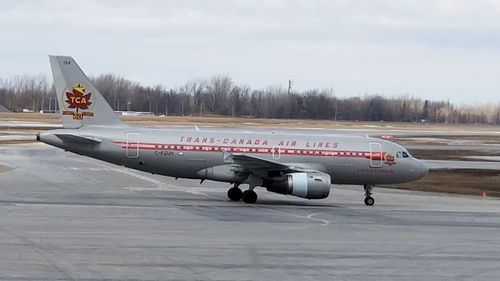 Airplane on airport runway against sky