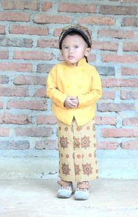 Portrait of boy standing against brick wall