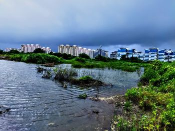 Scenic view of river by buildings against sky