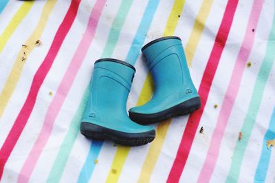 High angle view of rubber boots on multi colored sheet