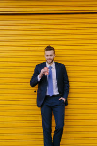 Portrait of young man standing against yellow wall