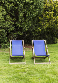 Empty chair on field against trees