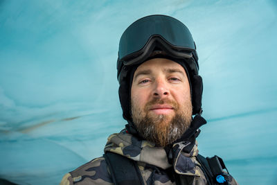 Portrait of man wearing ski googles against blue ice