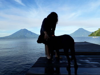 Horse standing by lake against sky