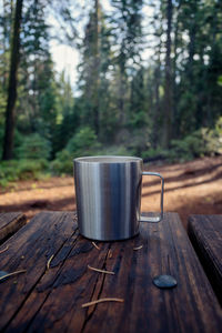 Coffee mug on table against trees in forest