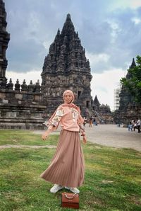 Woman with umbrella on temple against building