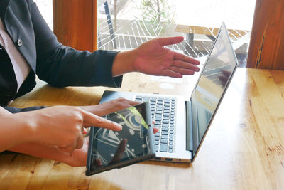 Cropped image of businesswomen using technologies at desk in office
