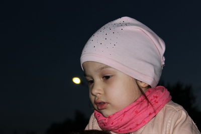 Portrait of girl looking away against sky at night