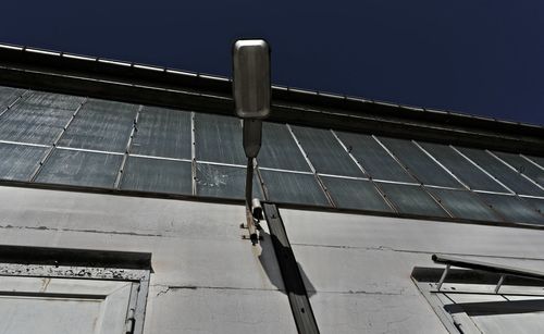 Low angle view of telephone pole against building against sky