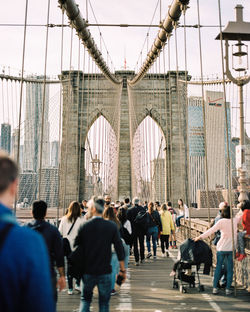 People walking on bridge in city against sky