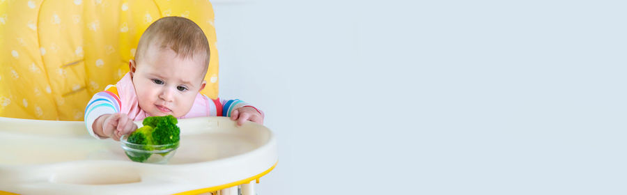 Portrait of cute girl eating food against white background